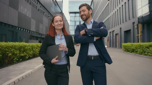 Two Professionals Walk and Talk in Urban Setting