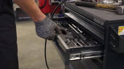 Closeup of a Man Opening a Box in a Metal Tool Cabinet at a Service Station