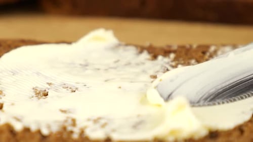 Buttering Dark Bread Slice with a Knife