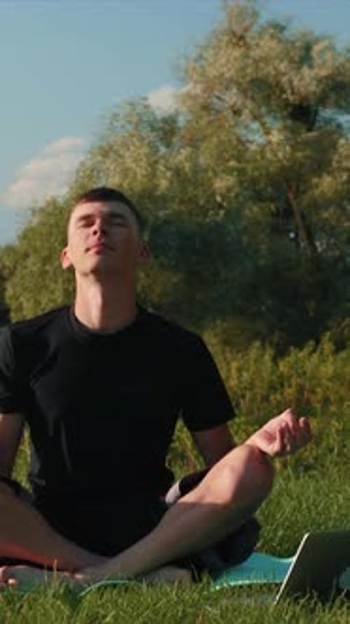 Meditating outdoors. Man doing yoga practice in morning park. Vertical video