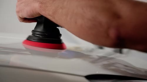 Closeup of Mechanic's Hand Buffing Car Hood Demonstrating Skilled Work in Vehicle Maintenance
