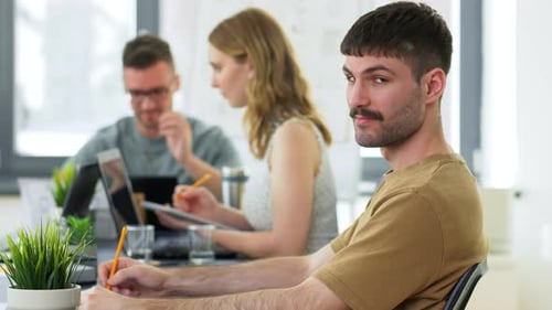 Happy smiling businessman works with colleagues in modern office