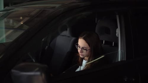 Young Businesswoman Coughs and Puts on a Mask While Sitting in a Car in the Parking Lot