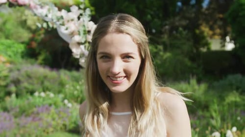 Smiling Young Woman in Wedding Dress in Garden