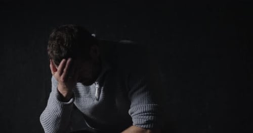 Portrait shot of male suffering from depression sitting alone at home in the dark, Mental health Con