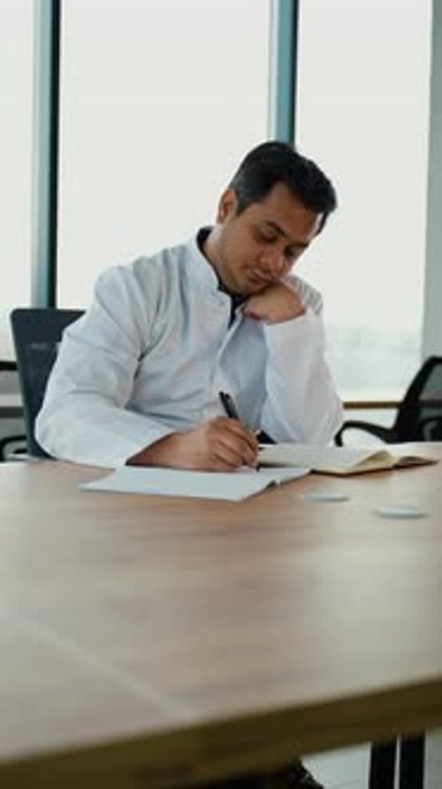 Stressed Frustrated Indian Doctor with Headache Sitting Alone at Work Desk in Hospital Sad Young Gp