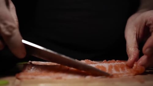 Slicing Fresh Salmon Fillet on a Dark Background