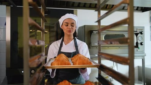 Woman Putting Croissants in Oven at Bakery