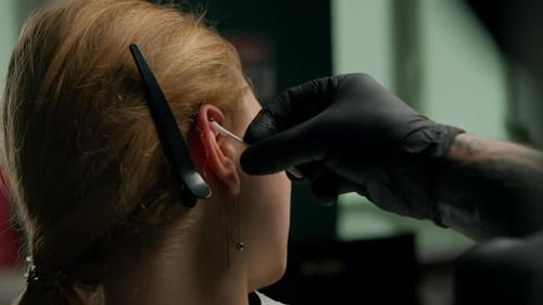 Piercing studio interior - piercing master makes a piercing to a girl, ear piercing