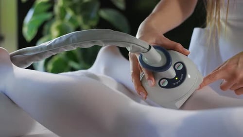 Close Up Hands Doing Anti Cellulite LPG Massage to Woman Body Lies on Its Side in a White Suit