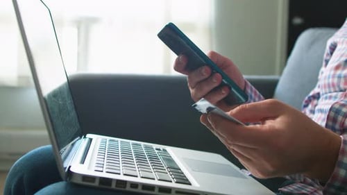 Person Uses Phone, Credit Card, and Laptop Indoors