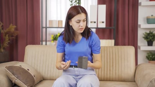 Young Woman Opens Empty Wallet, Looks Concerned