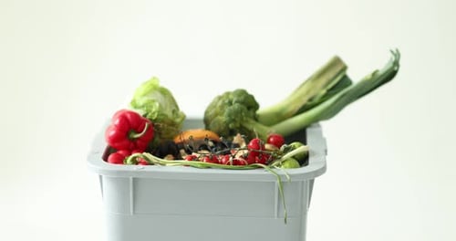 Woman throwing garbage into trash bin on white background, camera moving in. Waste sorting