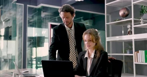 Male and female business professionals looking at laptop together during office meeting, working on