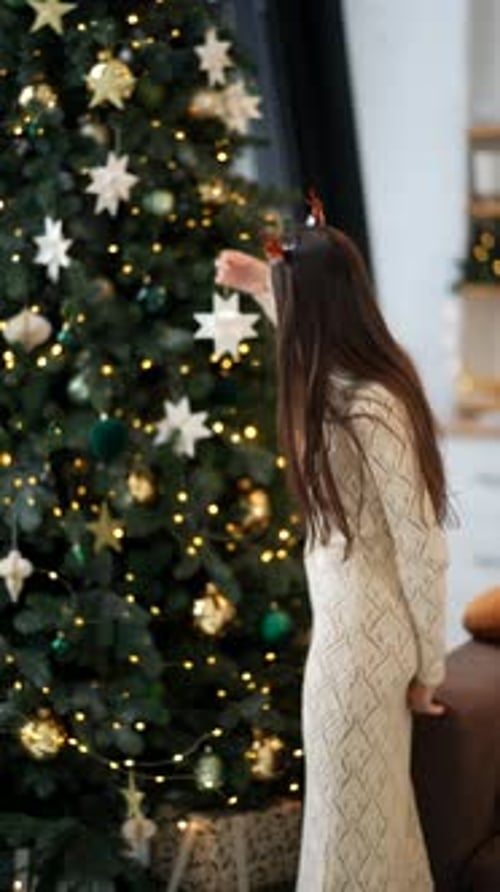 A Joyful and Festive Girl is Decorating for the Holiday Season with a Beautiful Star Ornament