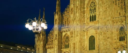 Duomo di Milano facade illuminated at night with vintage streetlamp nearby