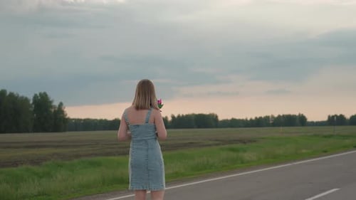 Rear View Woman Waving Colourful Pinwheel on Asphalt Road