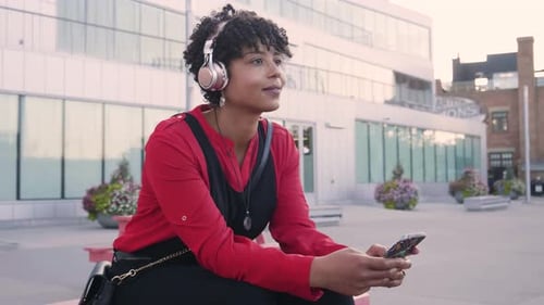 Smiling Woman With Headphones Using a Mobile Phone