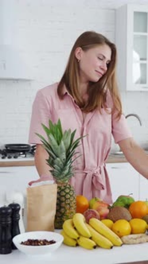 Young woman in the kitchen. Fresh fruit and vegetables on the table for dieting.
