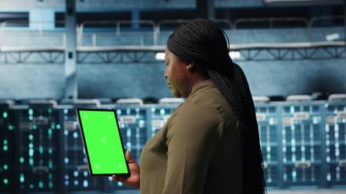 Rechenzentrumsspezialist überwacht Rechenzentrumsmetriken auf einem Greenscreen-Tablet