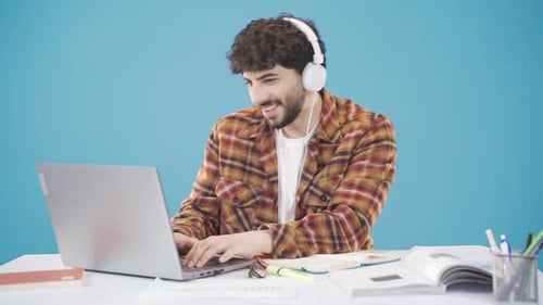University student doing homework at the desk, listening to music and studying with pleasure.