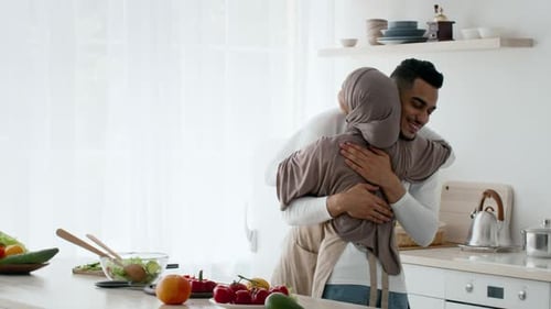 Couple Enjoys a Warm Embrace in a Cozy Kitchen Filled with Fresh Produce