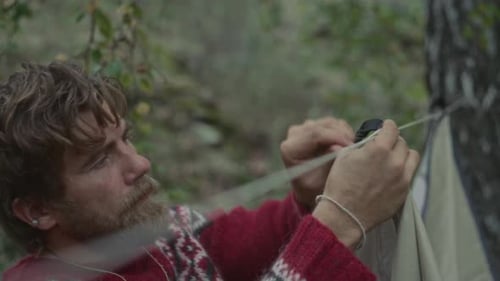 Man Assembling Tent Cord as Preparing Forest Campsite