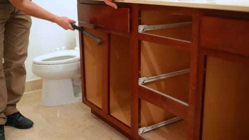 Construction Worker Using a Hammer to Break and Remove Bathroom Furniture Under Sink During