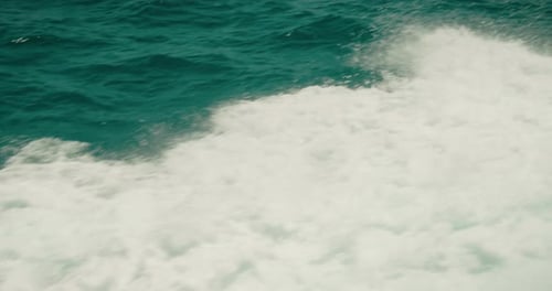 Schaumige Wellen in Türkistönen, die von einem fahrenden Boot aufgewirbelt werden, mit klarem Fokus auf dem Wasser.