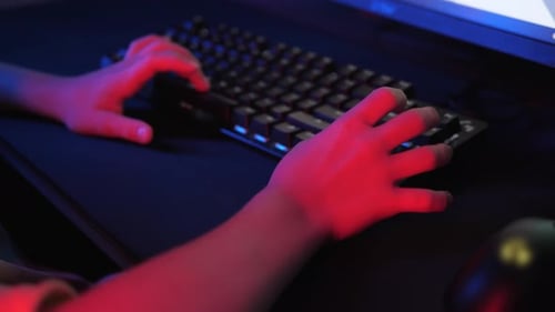 крупный план рук подростка быстро печатающих на механической клавиатуре и двигающих мышь