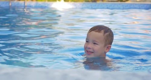 Cute little child bathing in outdoor swimming pool