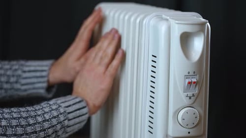 Unrecognizable Man Warming Hands with Electric Heating Radiator