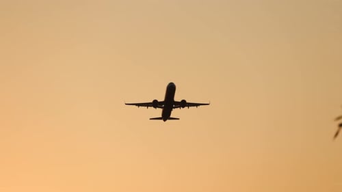 Airplane Flying at Sunset in Orange Sky