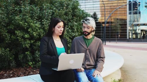 Business people sitting outside the office having a business meeting and using a laptop computer