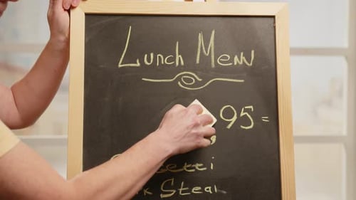 Price reduction. Manager of street cafe changes price tag for menu on chalkboard