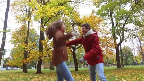 Happy young couple spinning around laughing in autumn park on romantic date