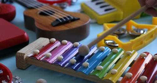 Child's musical instrument. Woman playing toy xylophone on light blue background, closeup