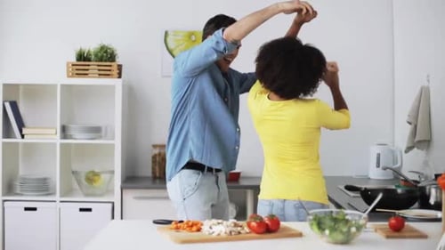 Happy Couple Dancing in Kitchen While Preparing Meal