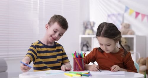 Cute little kids drawing with felt tip pens at white table indoors