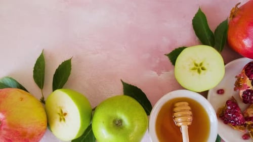 Fondo de fiesta de Año Nuevo judío de Rosh Hashaná con miel, granada y manzanas sobre fondo rosa