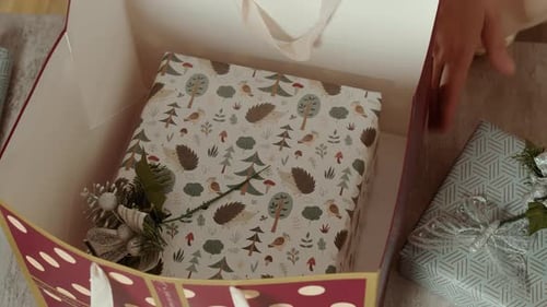 Woman Packing Christmas Gifts in Box at Home