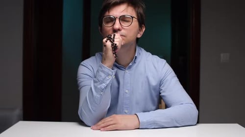 Man Praying with Prayer Beads Indoors