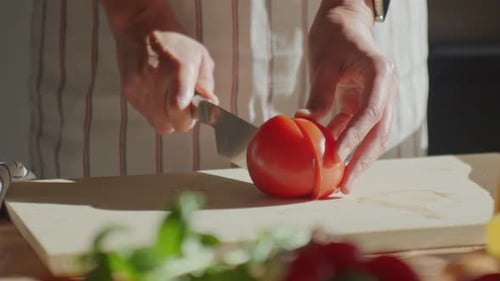 Tomato Being Sliced on a Wooden Cutting Board