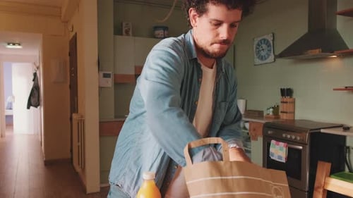 Young Adult Unpacking Groceries in Kitchen