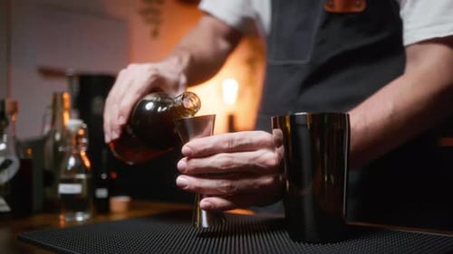 Bartender pouring liquor in a jigger. Perfect for showcasing cocktail preparation in a bar or restau