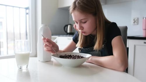 Girl Eating Bowl of Chocolate Cereal for Breakfast