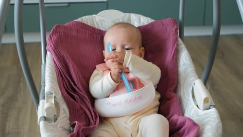 Adorable Baby in Swing Plays with Spoon