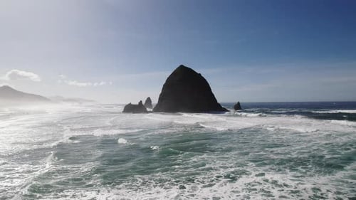 Misty mountains and a shadowy Haystack Rock dominate the coastline view