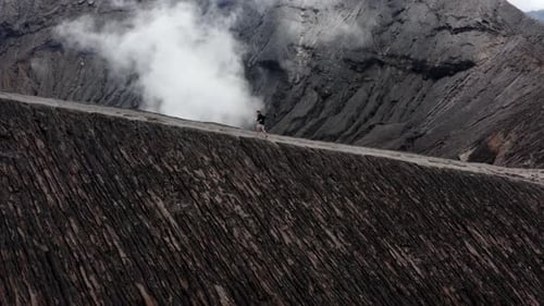 Active man running on edge of billowing Volcano in Indonesia