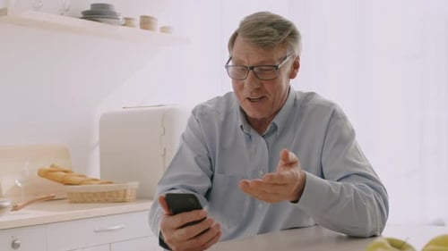 Senior Man Video Chatting in Bright Kitchen